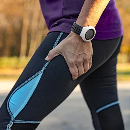 Close-up of a hand placed on the upper thigh of a person wearing athletic leggings and a wristwatch.